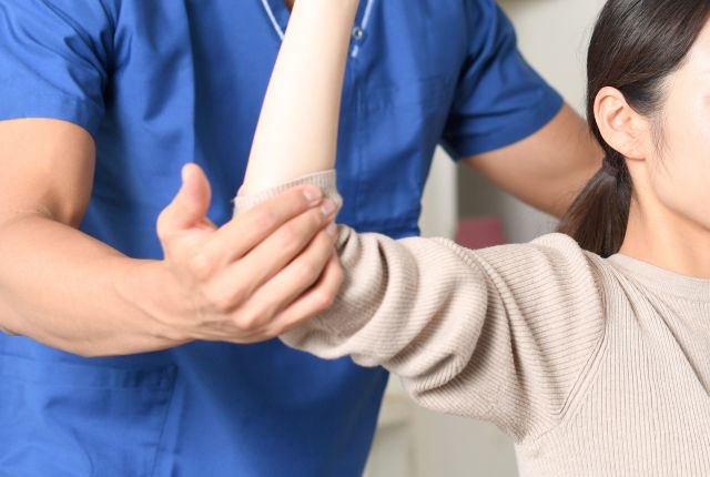 女性の肘の状態を確認するスタッフ