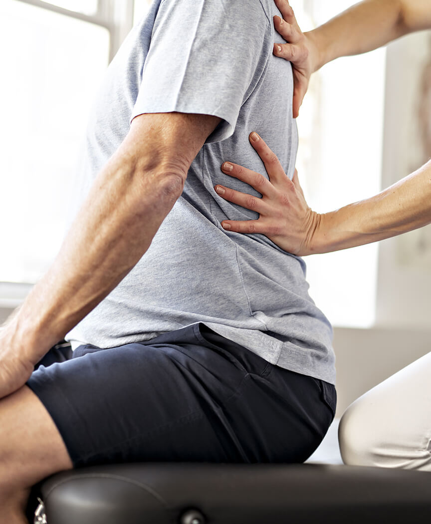 理学療法士に腰の状態を確認してもらう男性